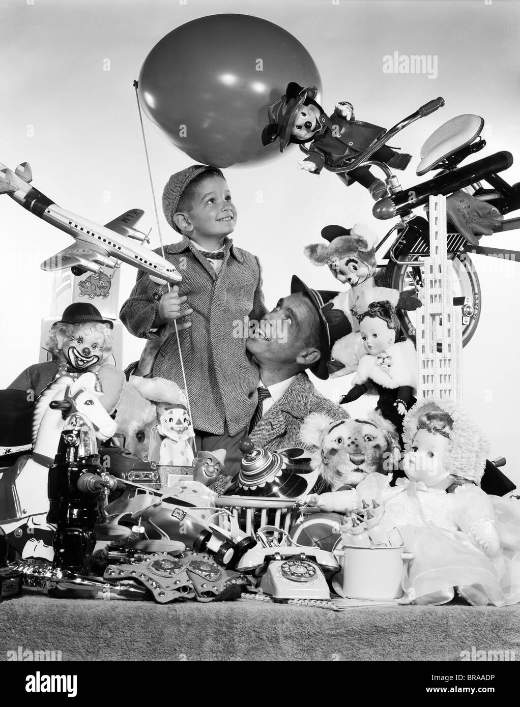 1950s FATHER WITH SON HOLDING BALLOON SURROUNDED BY TOYS & STUFFED ANIMALS Stock Photo
