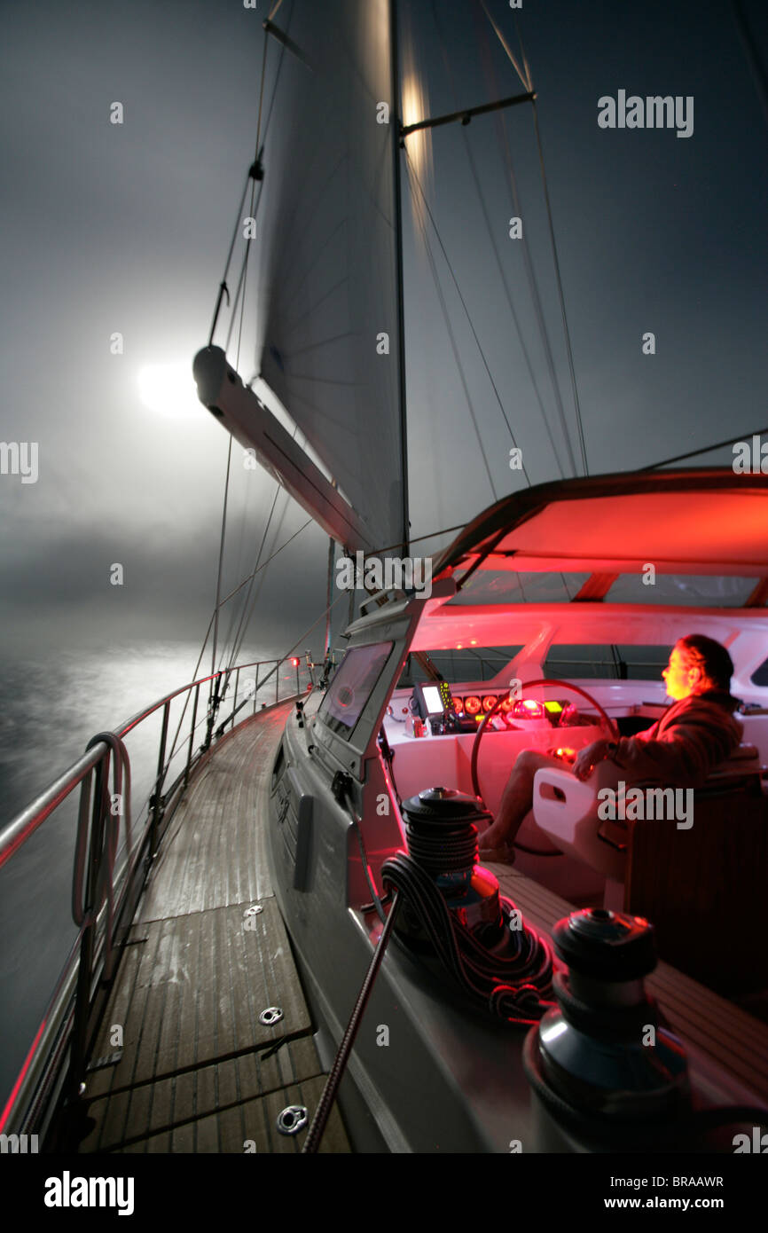 Man helming Amel 54 ketch 'Hollis' at night, on delivery from Martinique, Caribbean. 2006. Stock Photo