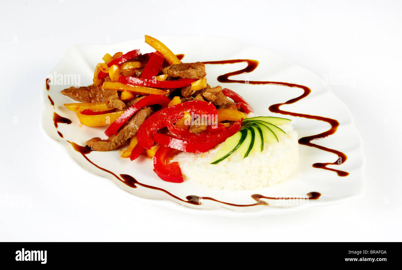 Grilled meat pieces with paprica and rice garnish isolated on a white plate Stock Photo