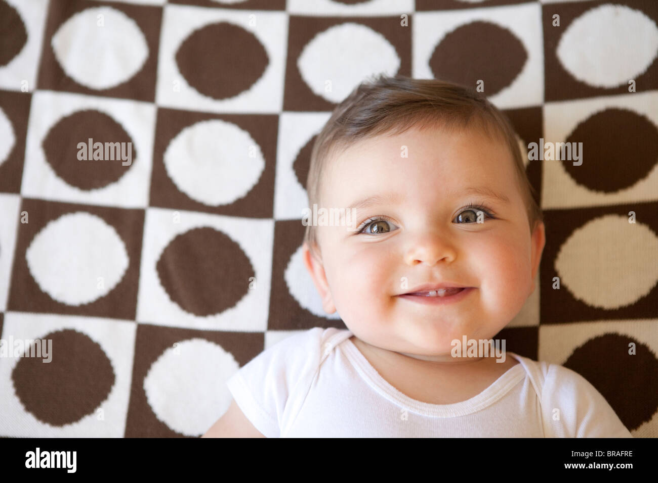 Smiling baby on brown and white blanket Stock Photo