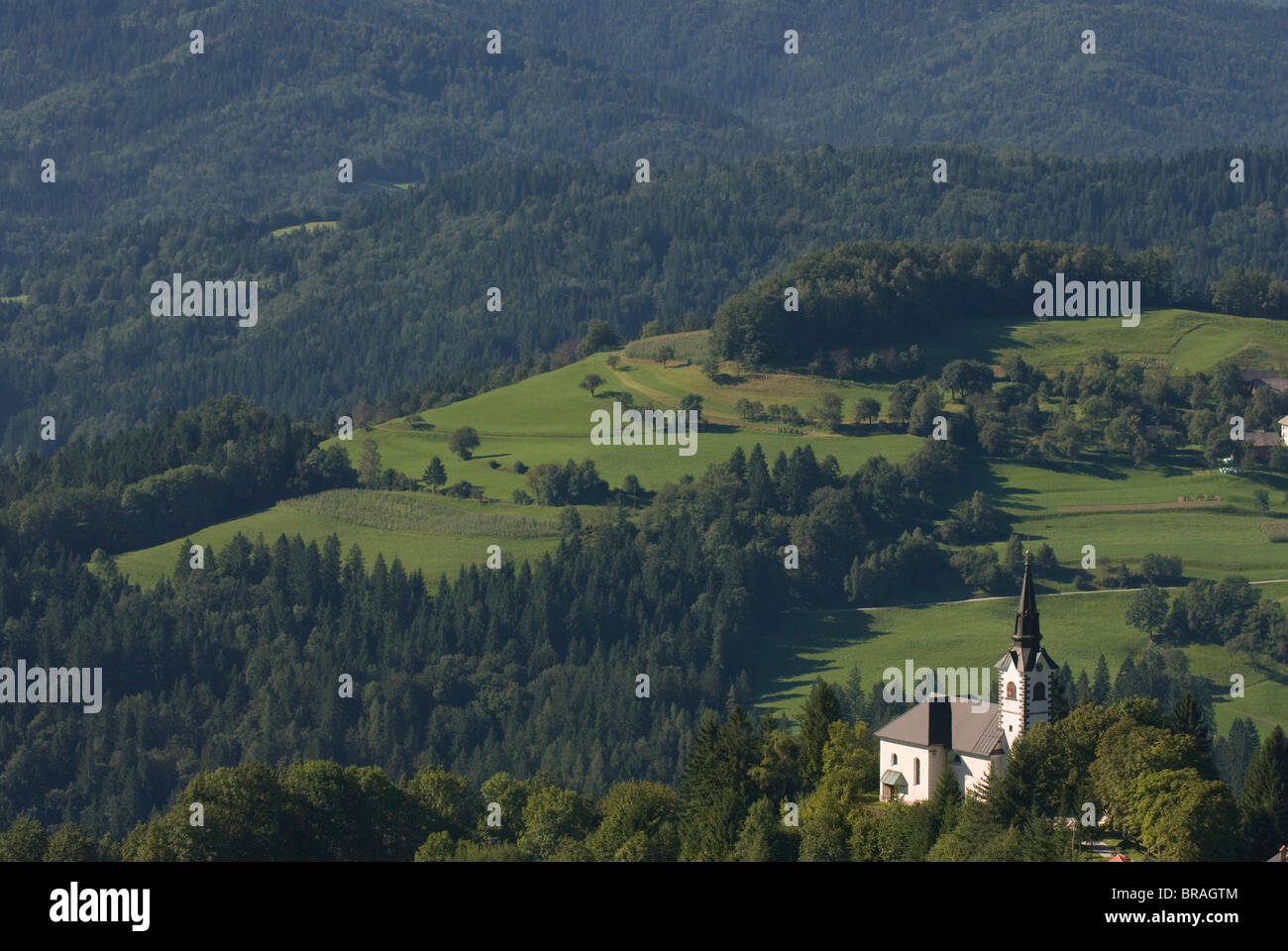 Church standing in valley of vast hill landscape, Sofja Loka, Slovenia, Europe Stock Photo