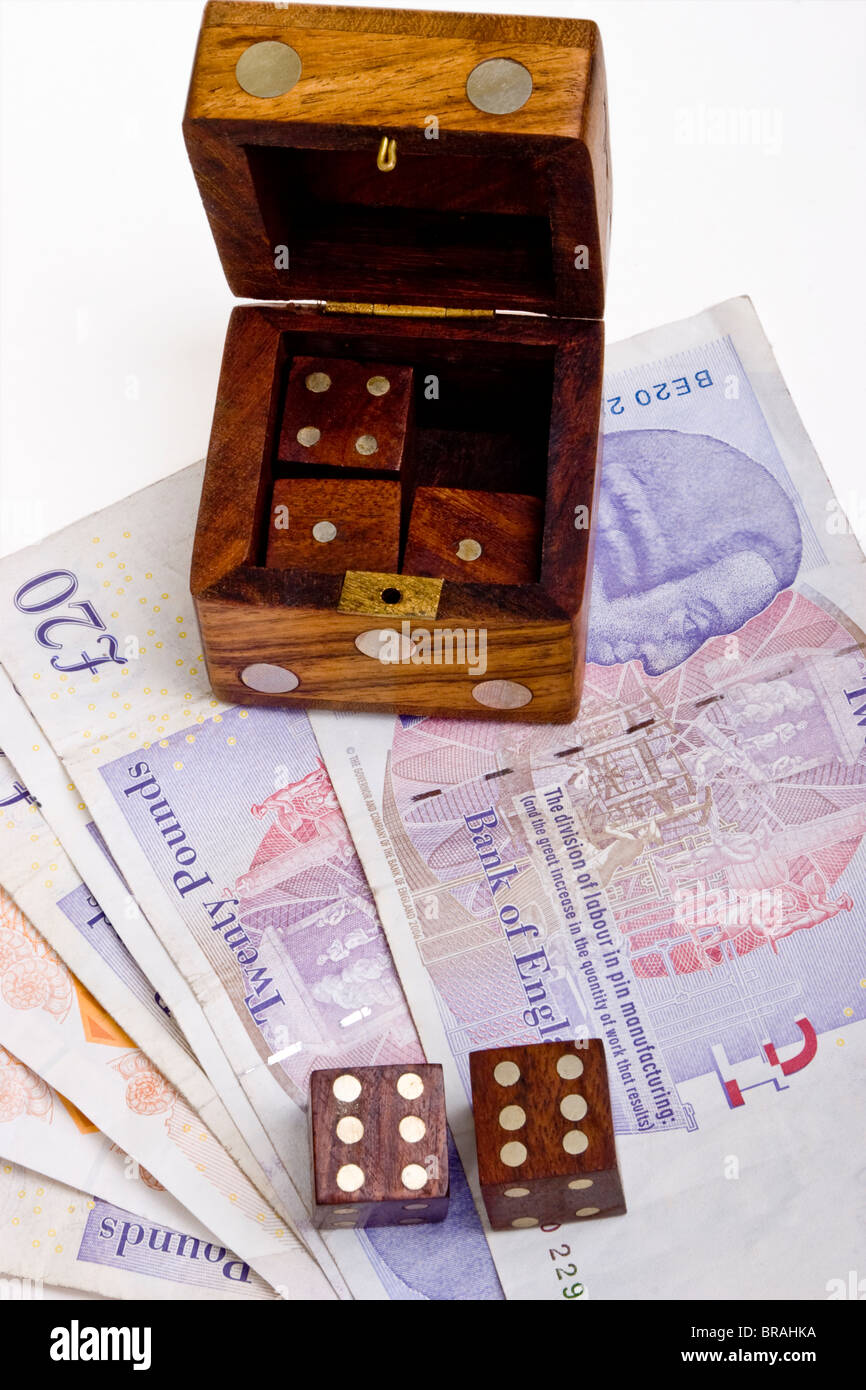 Wooden die or dice box with two dice on British sterling pound notes
