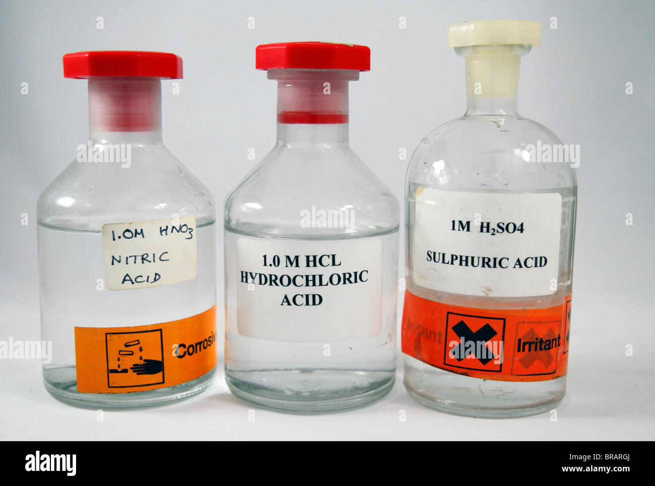 Three bottles of 1 molar (1.0M) school acids as used in England: Nitric Acid, Hydrochloric Acid and Sulphuric acid. Stock Photo