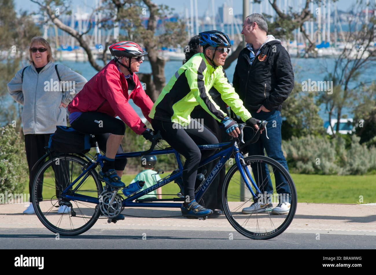 Two men riding a tandem bicycle along the Esplanade at St Kilda Beach in Melbourne Australia