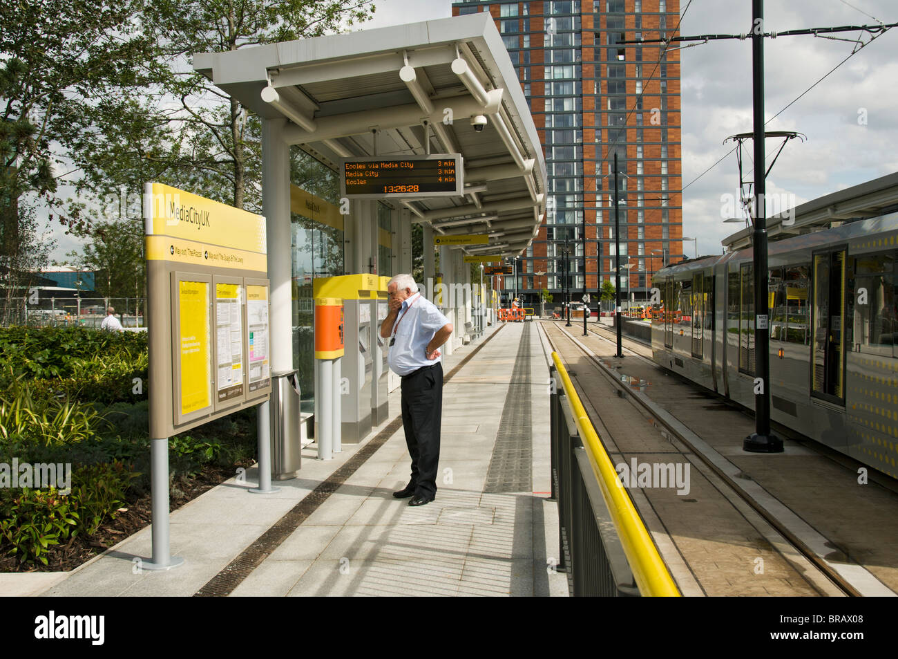 Man reading a sign at the Metrolink tram station at MediaCityUK ...