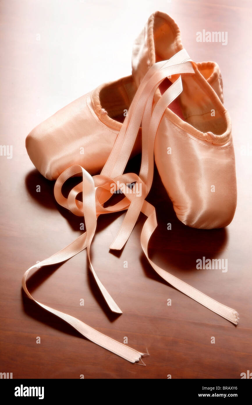 Pink satin ballet shoes on dark floor Stock Photo