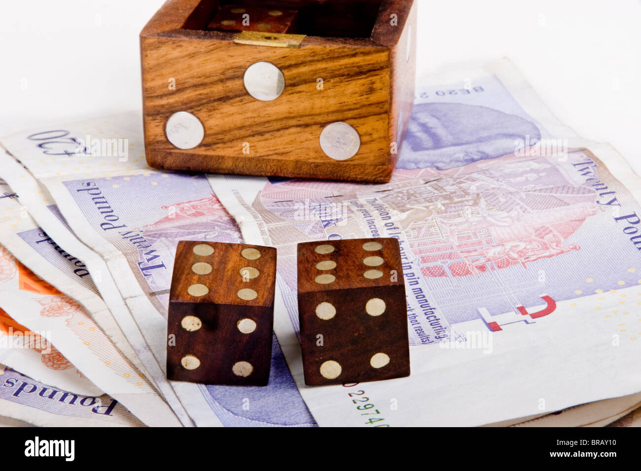 Wooden die or dice box with two dice on British sterling pound notes