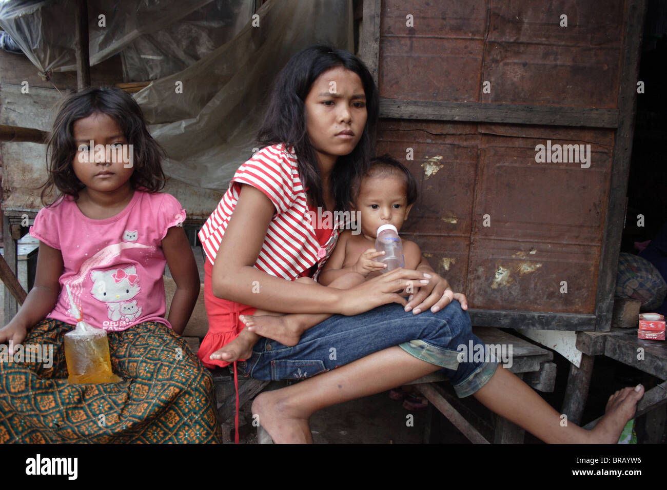 A 14 year old girl sits with her siblings on the porch of her home in a slum  in Phnom Penh, Cambodia Stock Photo - Alamy