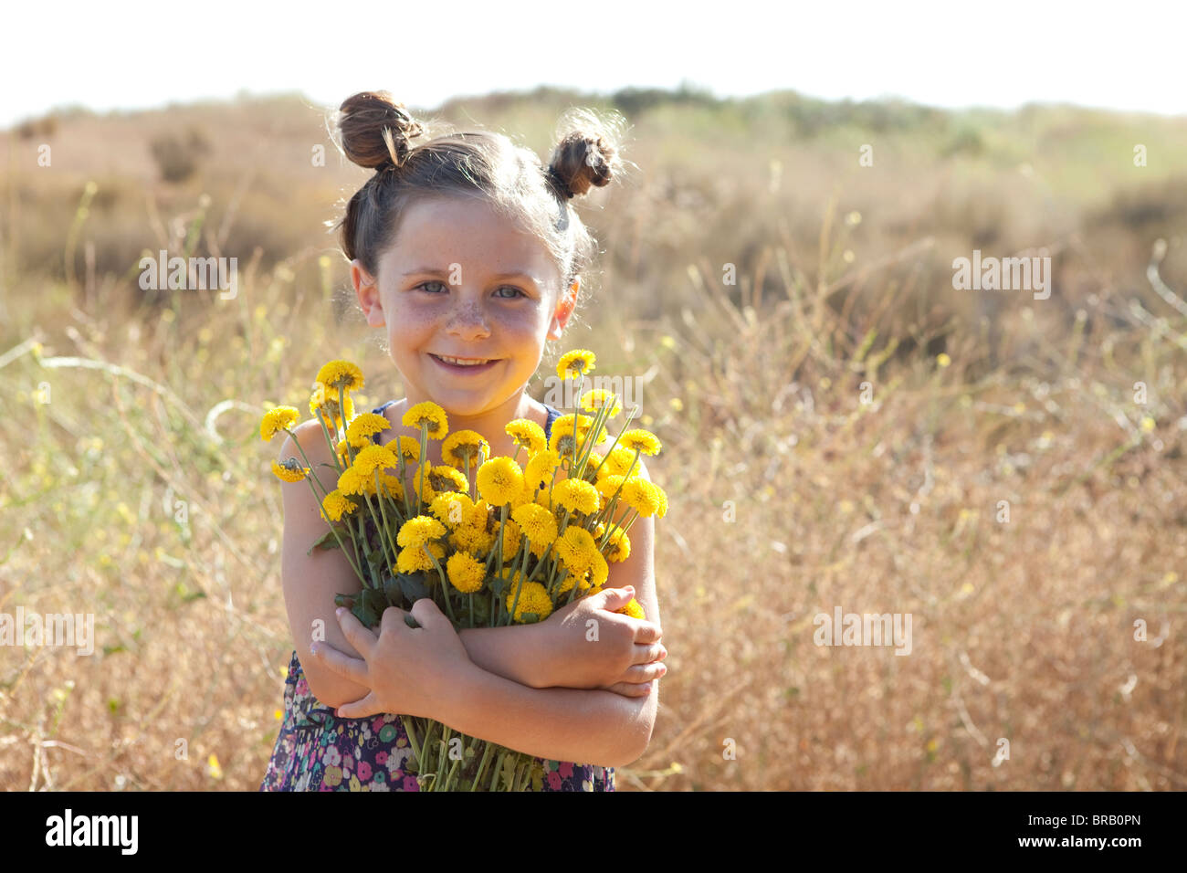Young girl with an armful of yellow flowers Stock Photo