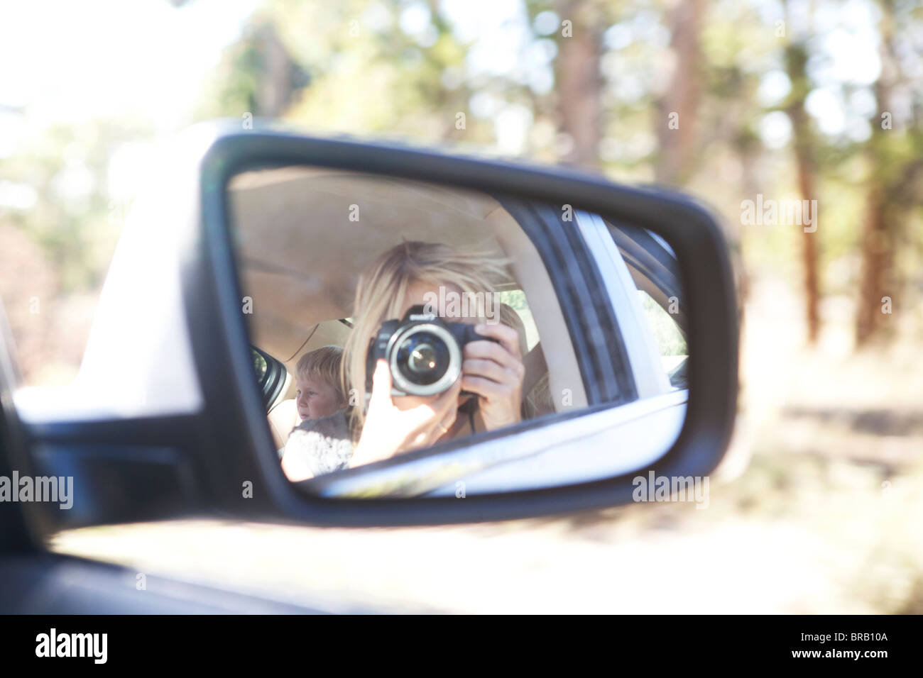 Woman taking pictures in side mirror of car Stock Photo