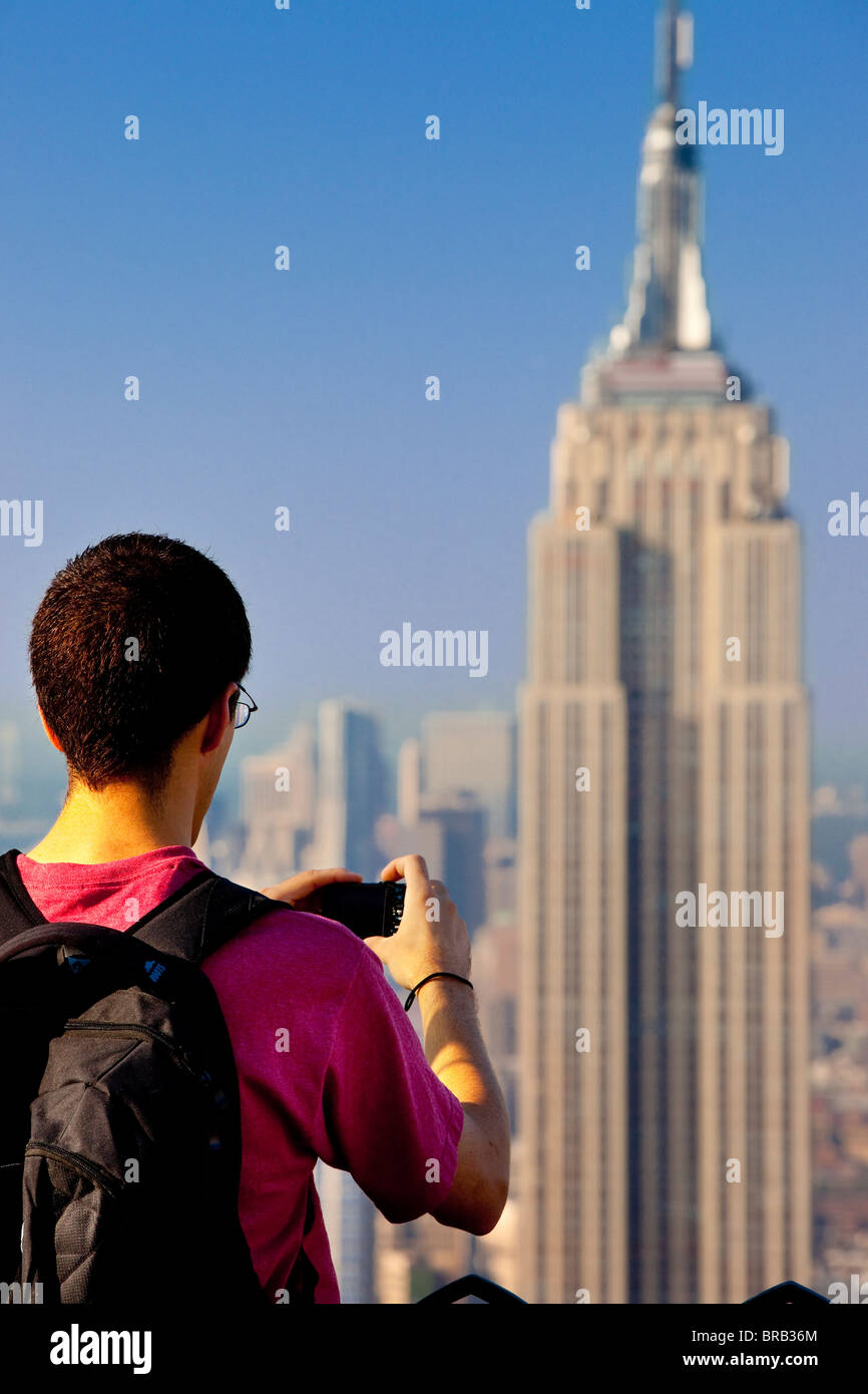 Tourist capturing a photo of the Empire State Building from the top of the Rockefeller Building, Manhattan New York City USA Stock Photo