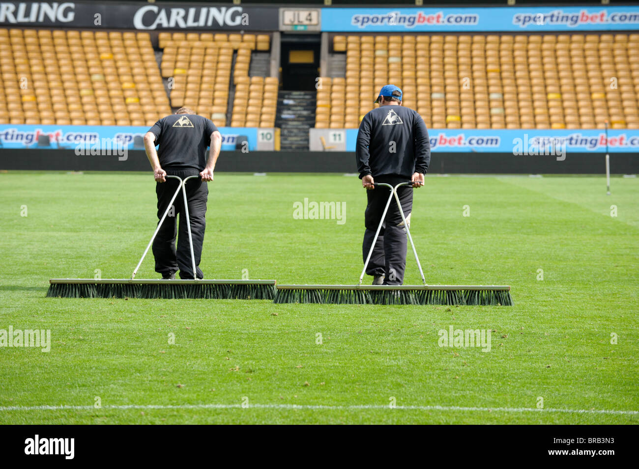 Two groundsmen brush the football pitch at Wolve's homeground Molineux