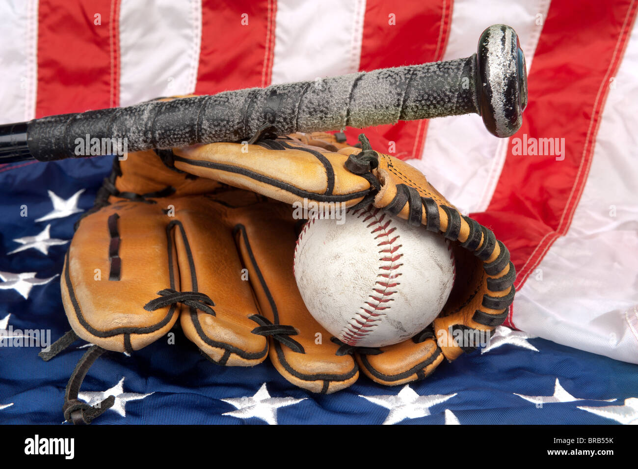 A baseball glove, baseball and bat on an American flag, symbolizing a
