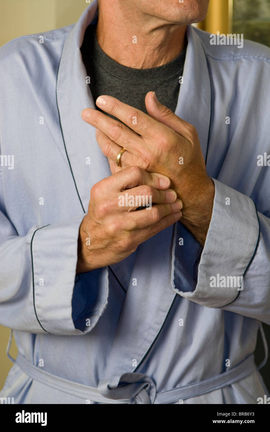 man in bathrobe wringing hands in pain Stock Photo