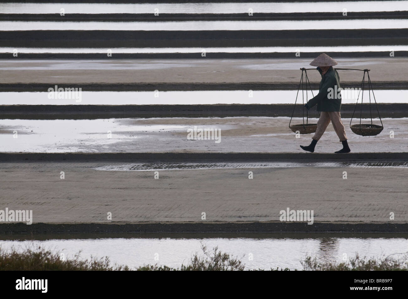 Woman carrying salt on salt workings, Vietnam, Indochina, Southeast Asia, Asia Stock Photo