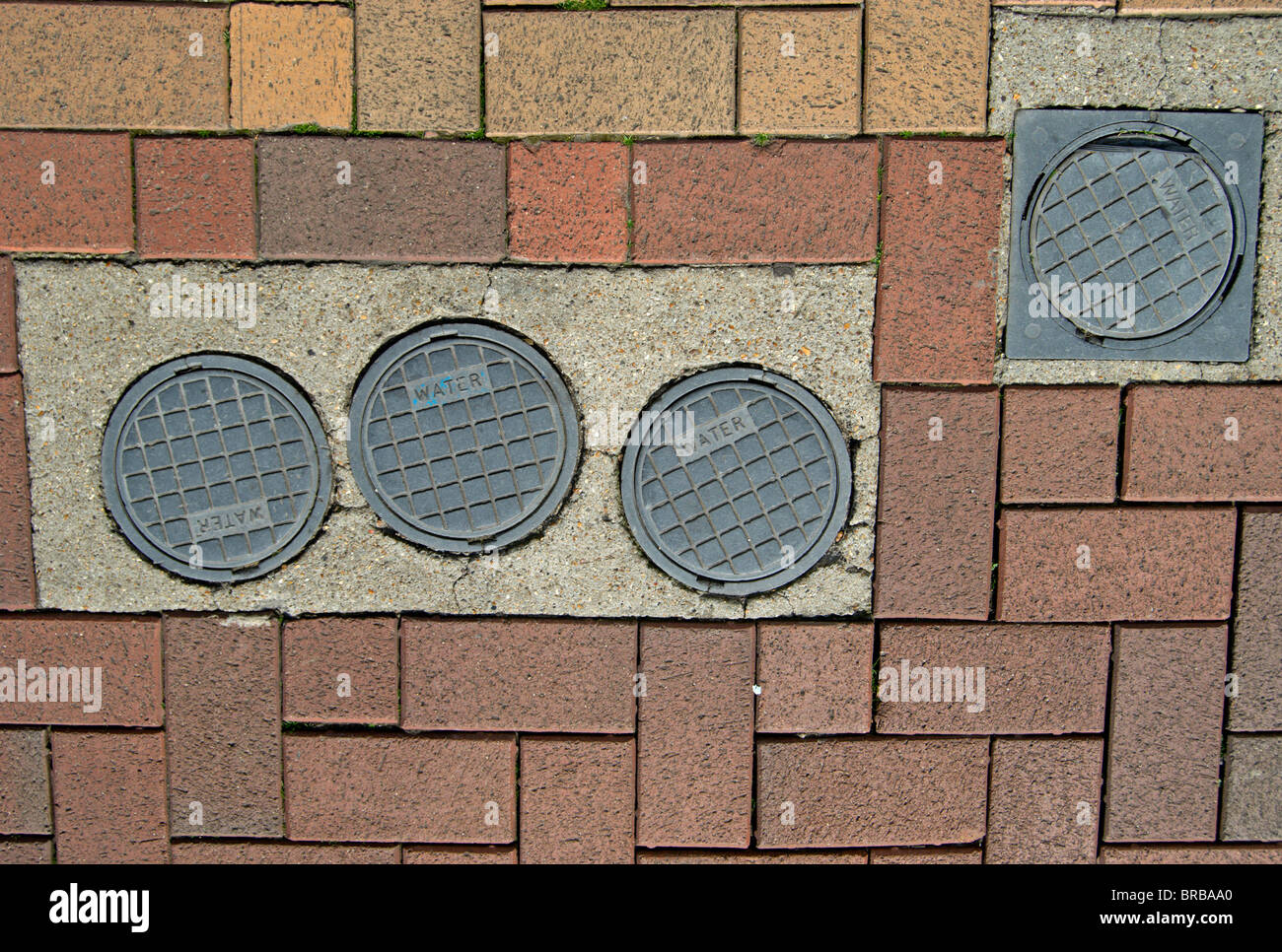 water main covers on a brick-paved street in putney, southwest london, england Stock Photo