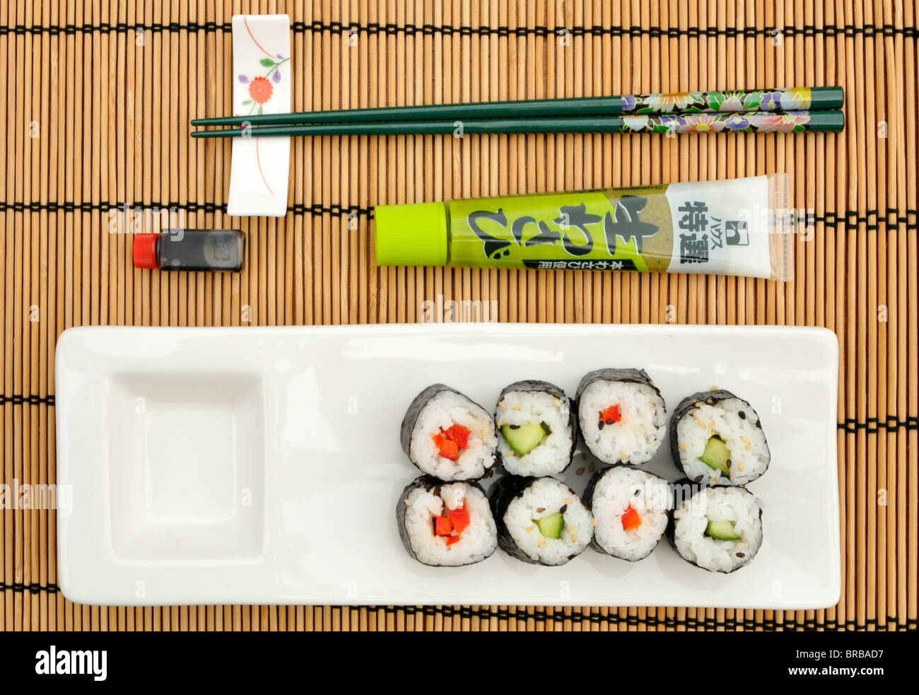 Red pepper and cucumber maki sushi, wasabi, soya sauce and a pair of chopsticks. Stock Photo