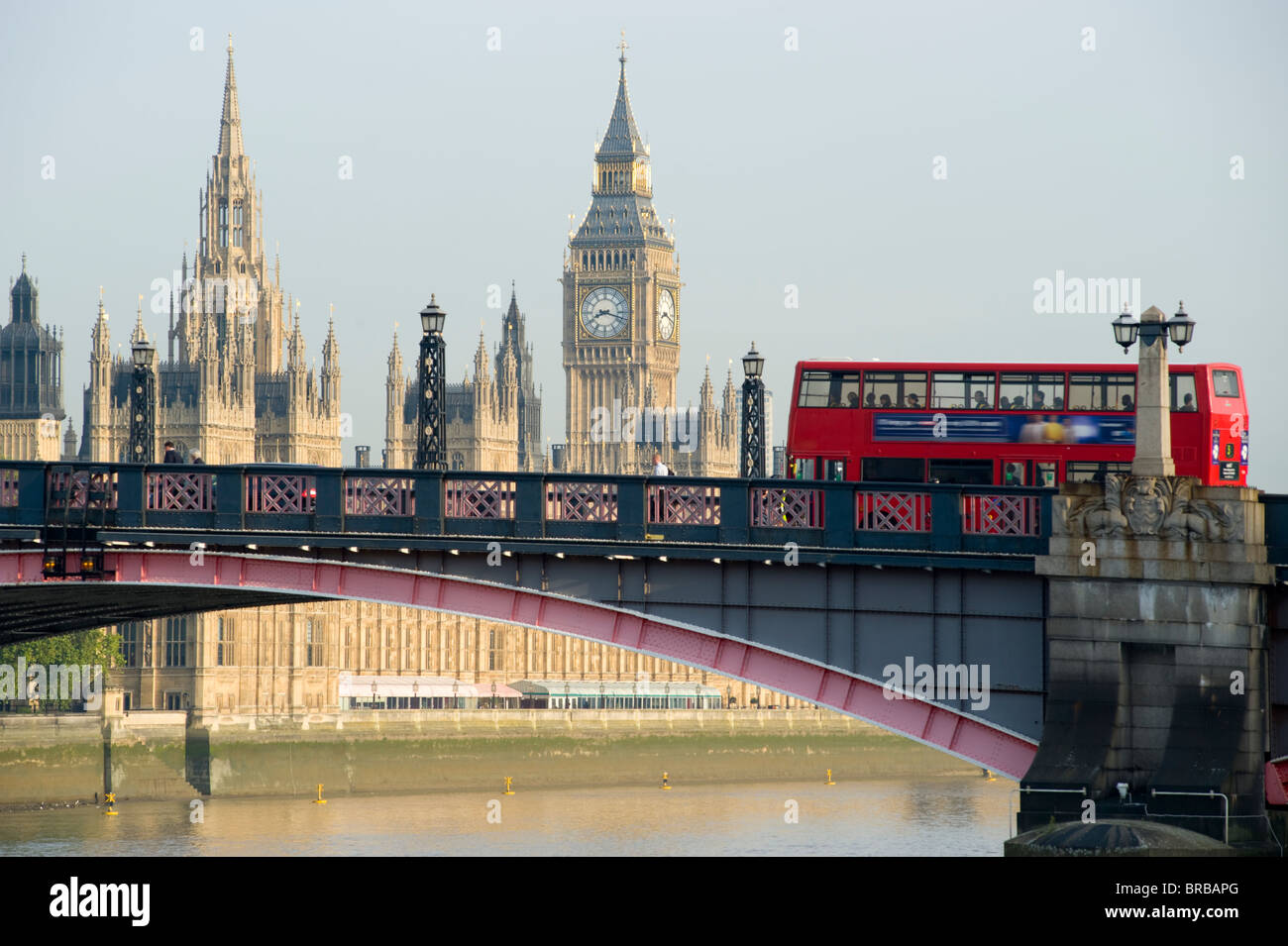 A London bus crossing Lambeth bridge over the Thames river with the Palace of Westminster in the background. London, England. Stock Photo