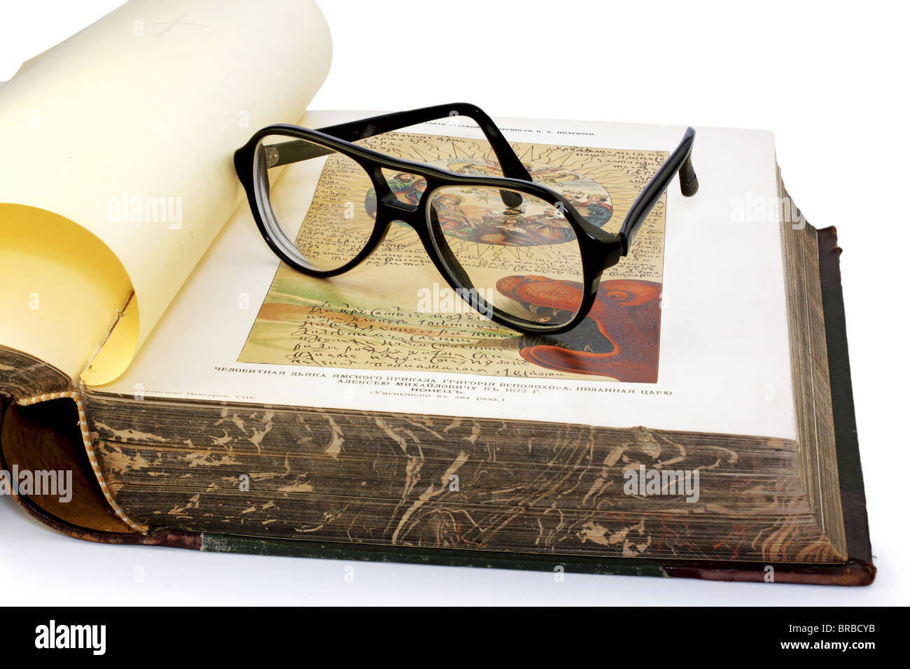 An open old book and black spectacles on it closeup Stock Photo