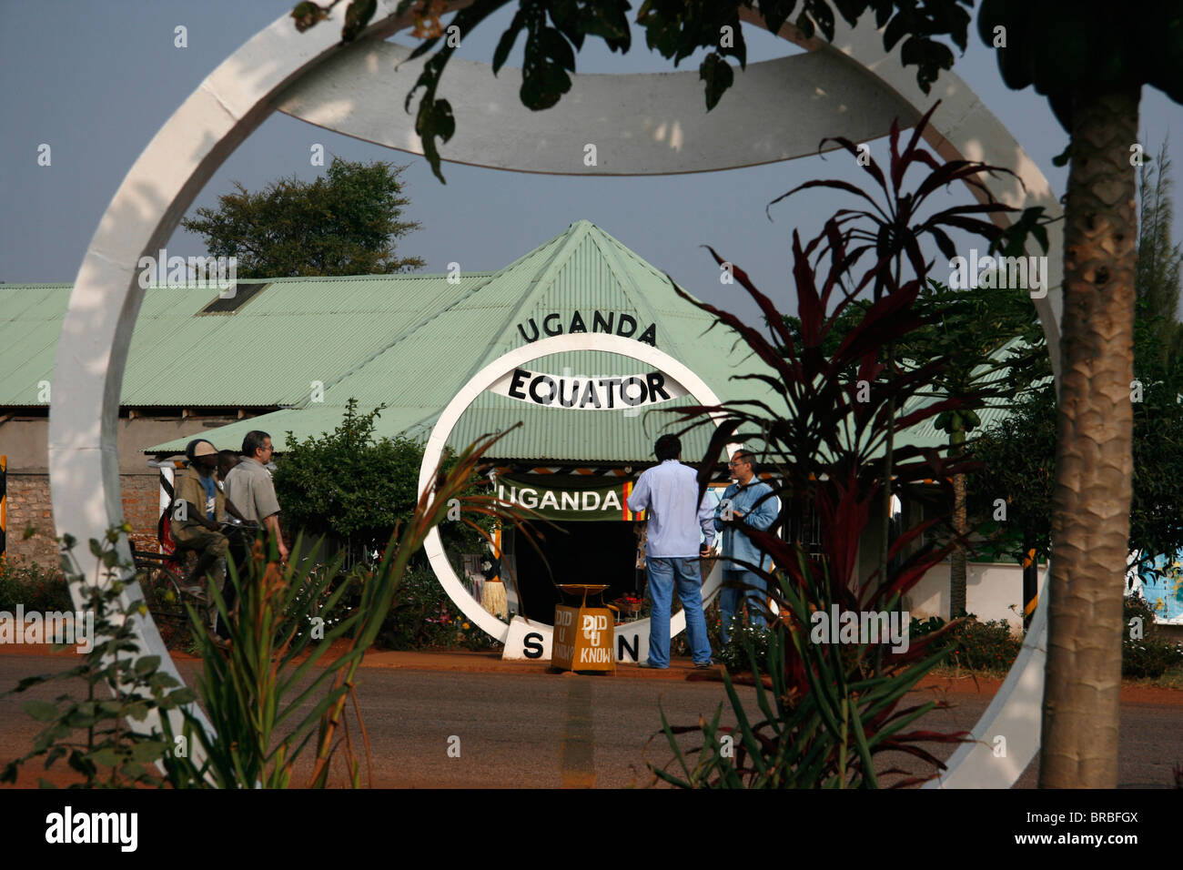 Equator crossing on Masaka Road, Uganda, with shops and tourists in the background. Stock Photo