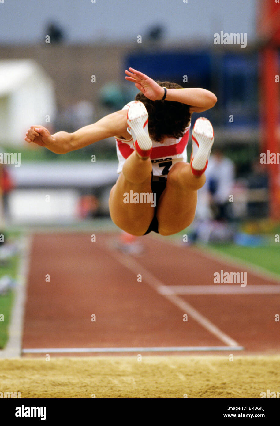 Female long jumper enters sand pit Stock Photo