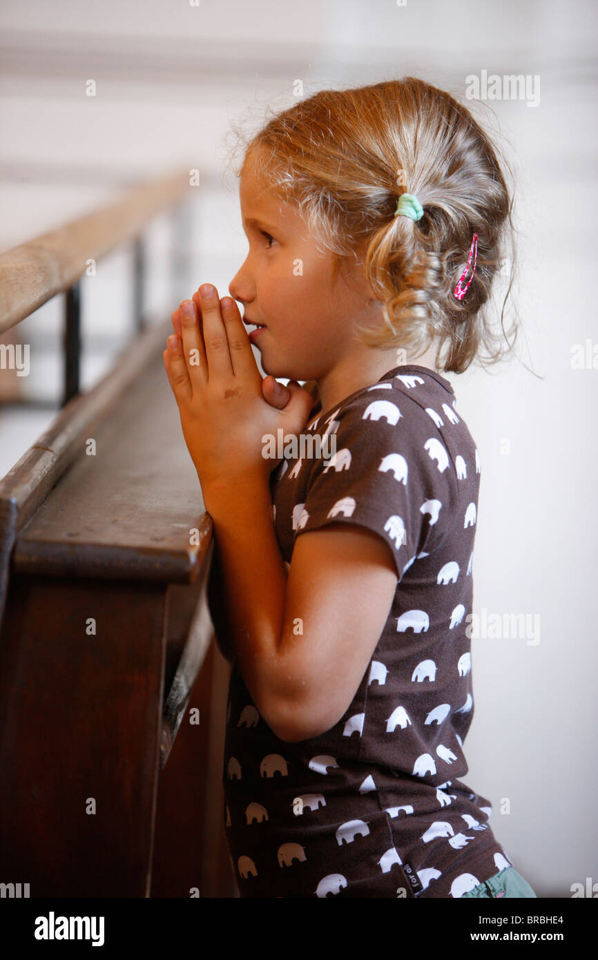 Girl praying in church, Saint Nicolas de Veroce, Haute Savoie, France Stock Photo