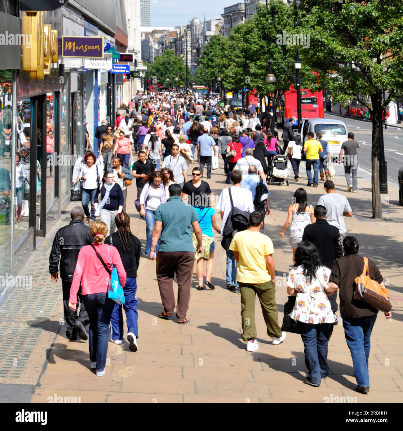 Crowd of shoppers & tourists view from above walking on busy Oxford Street pavement famous West End shopping street & shop fronts summer day London UK Stock Photo