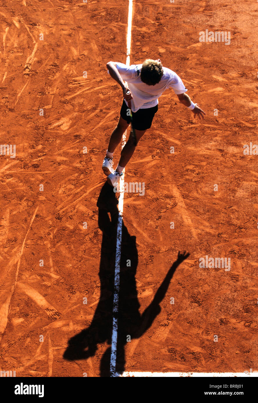Tennis player serves on a clay court tennis court Stock Photo