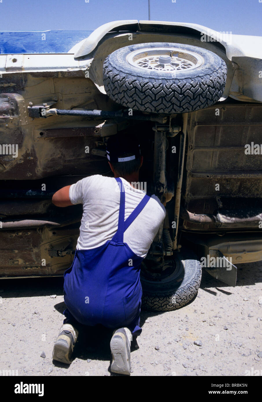 Man fixing an offroad car flipped on it's side Stock Photo Alamy