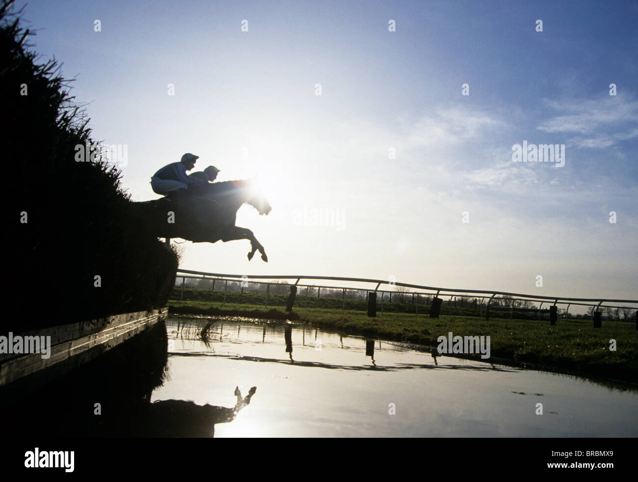 Steeplechase jockeys jump their horses over water jump Stock Photo Alamy