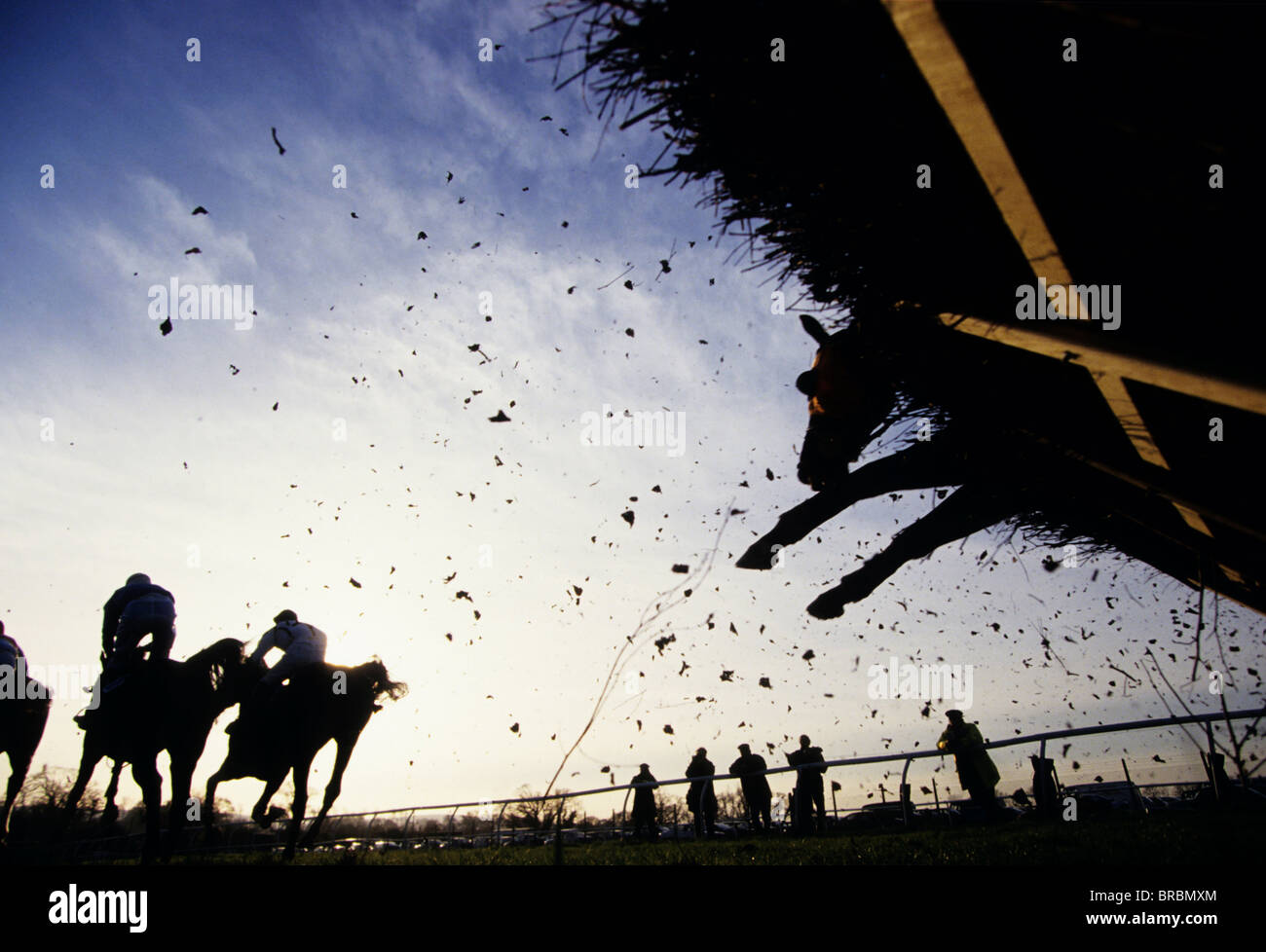 Jockeys and their horses clear thicket fence from under fence view Stock Photo