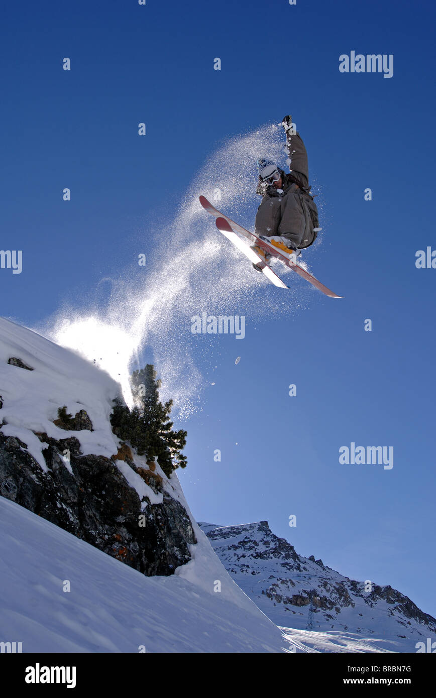 Skier jumping off a rock in St Moritz, Switzerland whilst spinning and grabbing their ski Stock Photo
