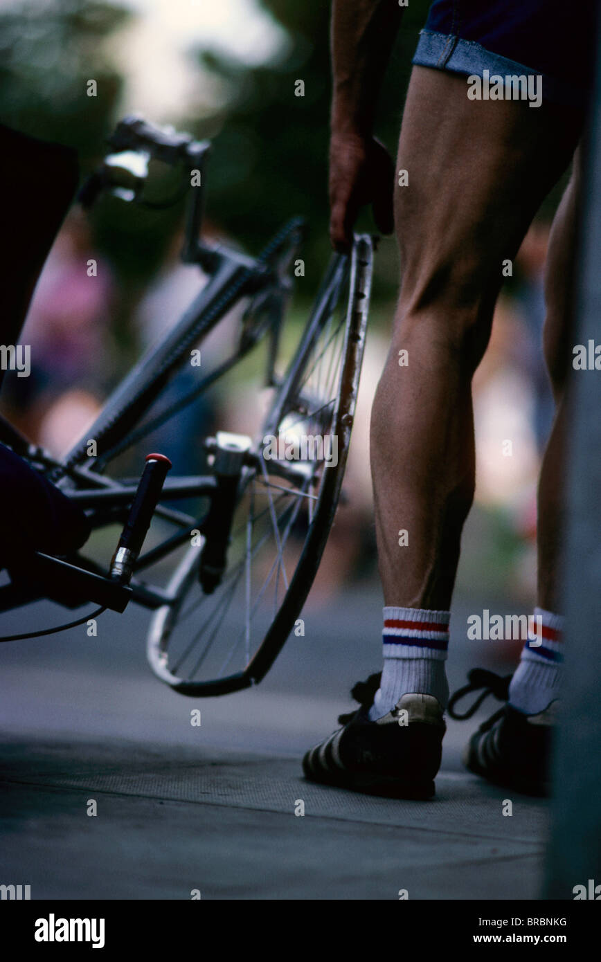 Cyclist stands and looks at his bike wheel damaged during the race Stock Photo