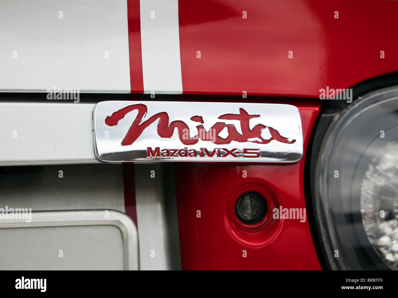 chrome plate with Miata logo on back of red Mazda MX-5 in racing trim Stock Photo