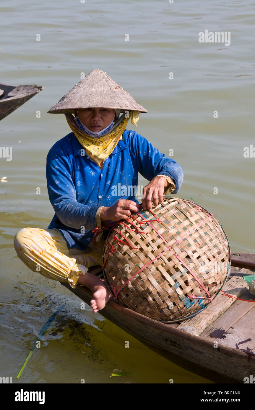 Traditionally dressed Vietnamese women repairing her basket, Hoi An, Vietnam, Indochina Stock Photo