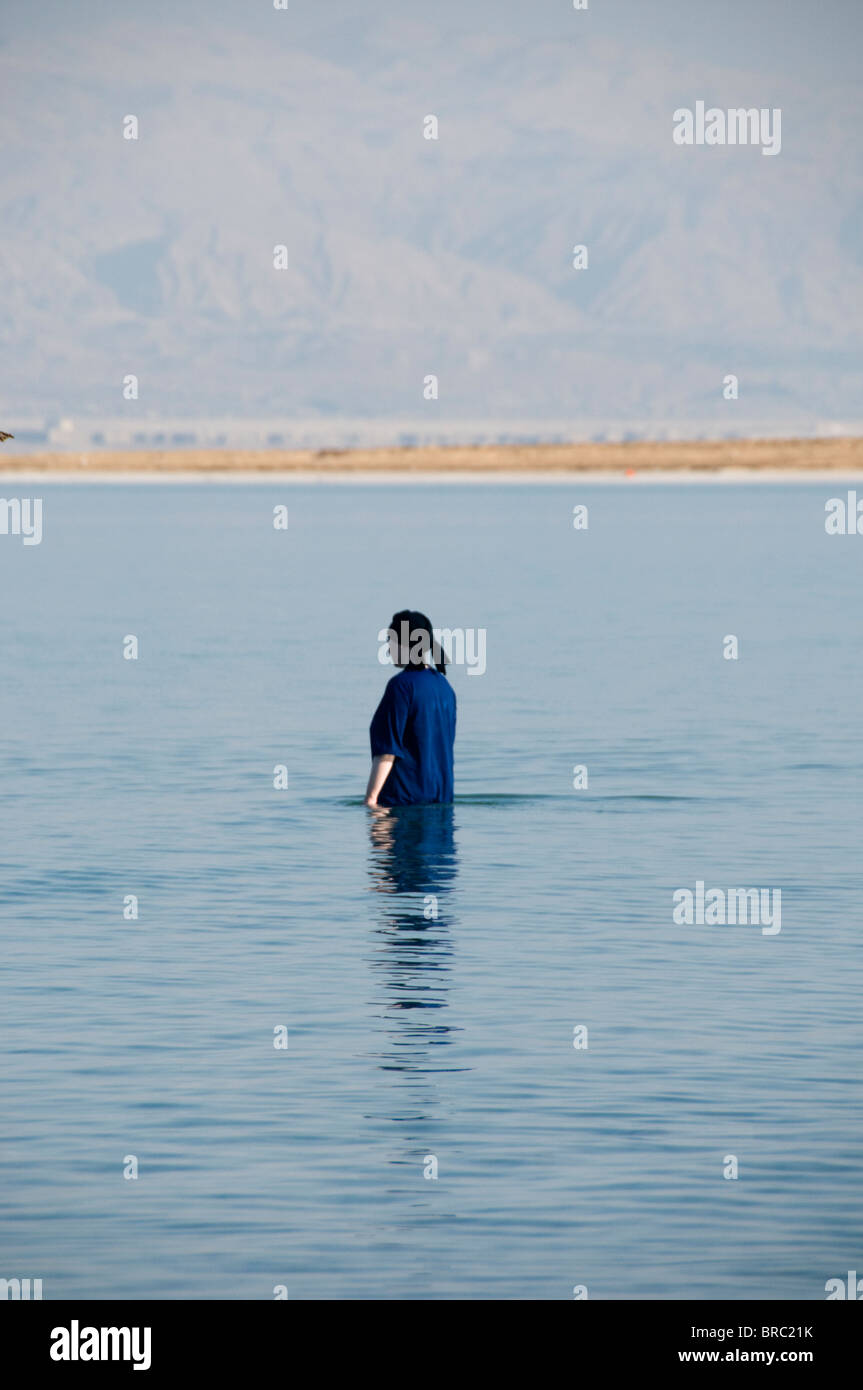 Back view of religious Jewish woman fully dressed, bathing in the Dead Sea Stock Photo