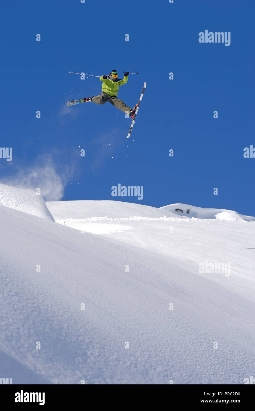 Skier jumps whilst performing an oldschool daffy freestyle trick in the powder snow in Laax, Switzerland Stock Photo