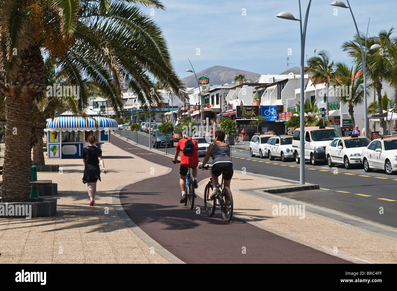 dh  PUERTO DEL CARMEN LANZAROTE Tourist walking and cyclists on pushbikes cycle path pavement Stock Photo