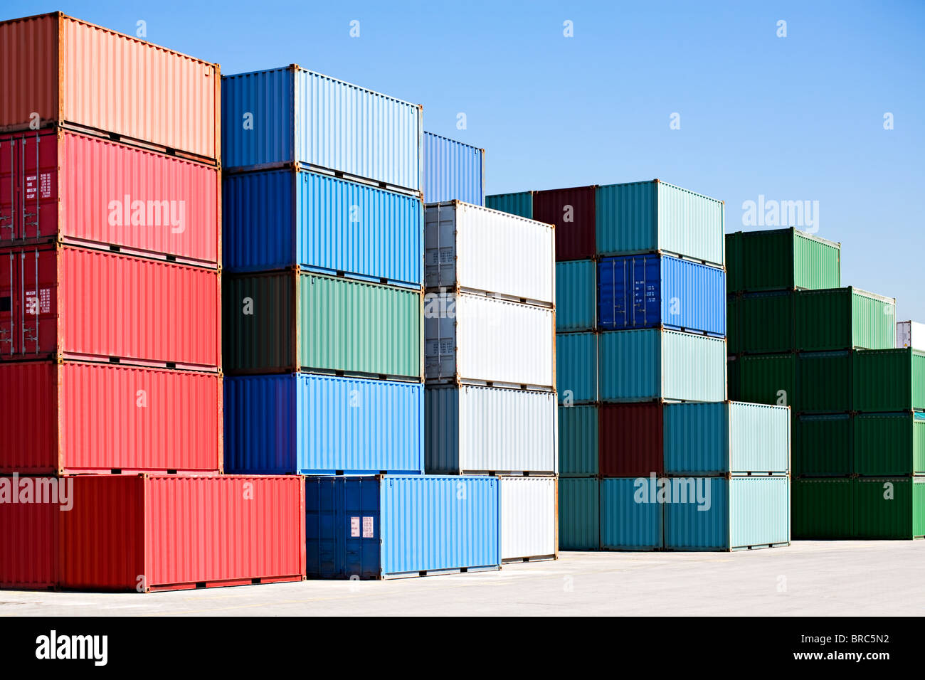 cargo shipping containers stacked at harbor freight terminal under clear blue sky Stock Photo