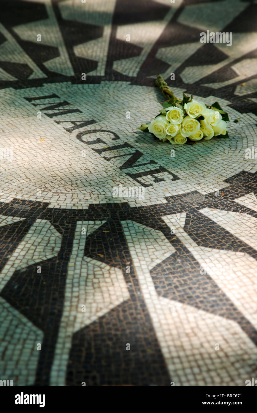 White roses placed on 'Imagine' - the John Lennon Memorial mosaic in Strawberry Fields inside Central Park, New York City USA Stock Photo