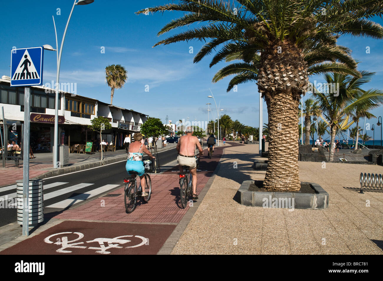 dh  PUERTO DEL CARMEN LANZAROTE Tourist couple cyclists on pushbikes cycle path pavement holiday spain couples bicycle riding cycles Stock Photo