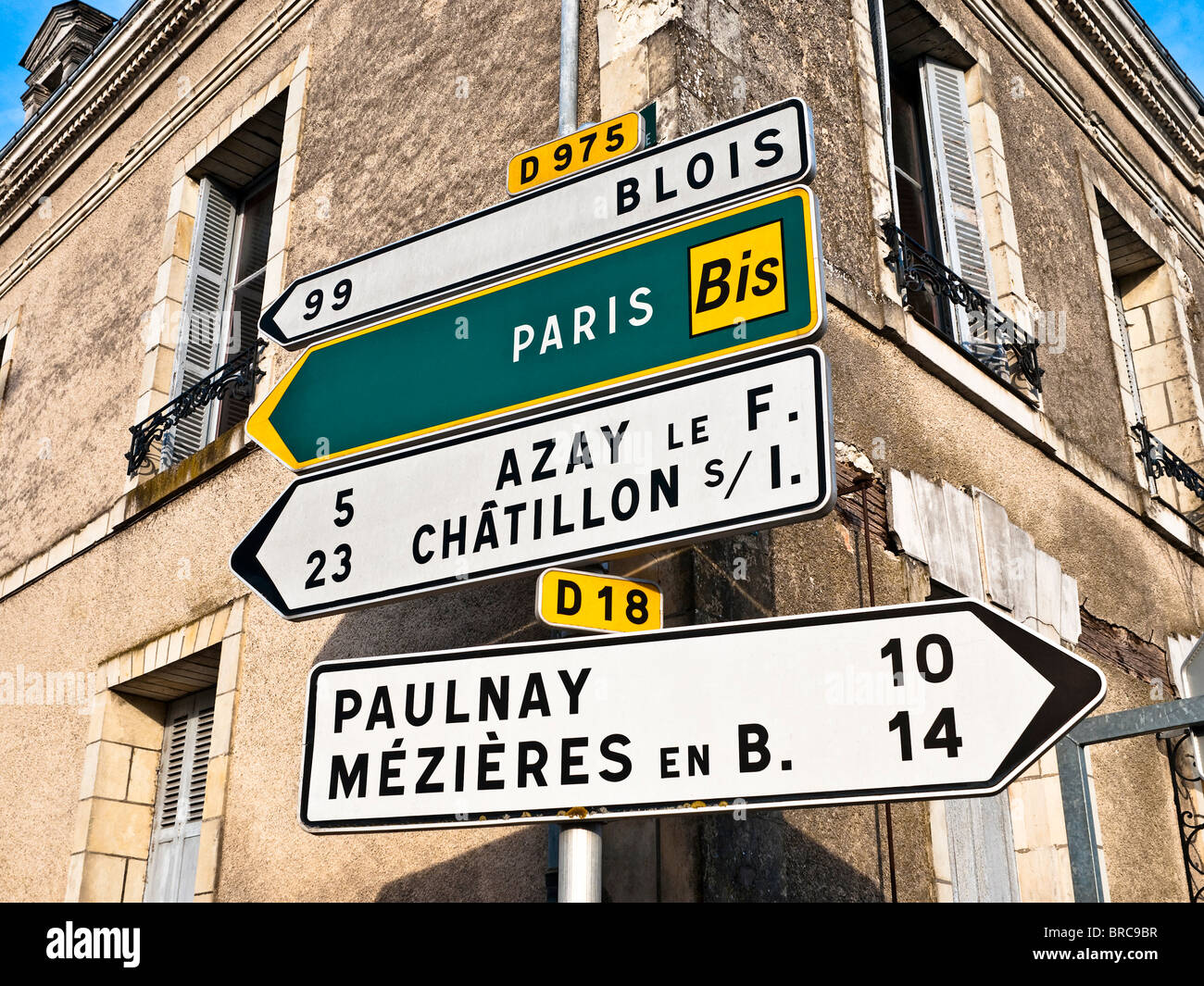 Visual pollution / modern route direction signs in front of old buildings - Indre, France. Stock Photo