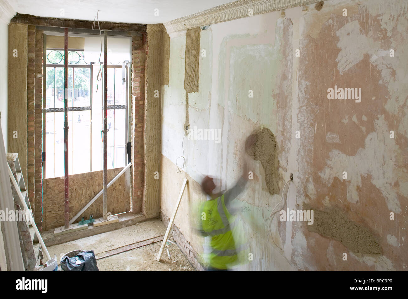 Worker filling holes in wall on building site Stock Photo Alamy