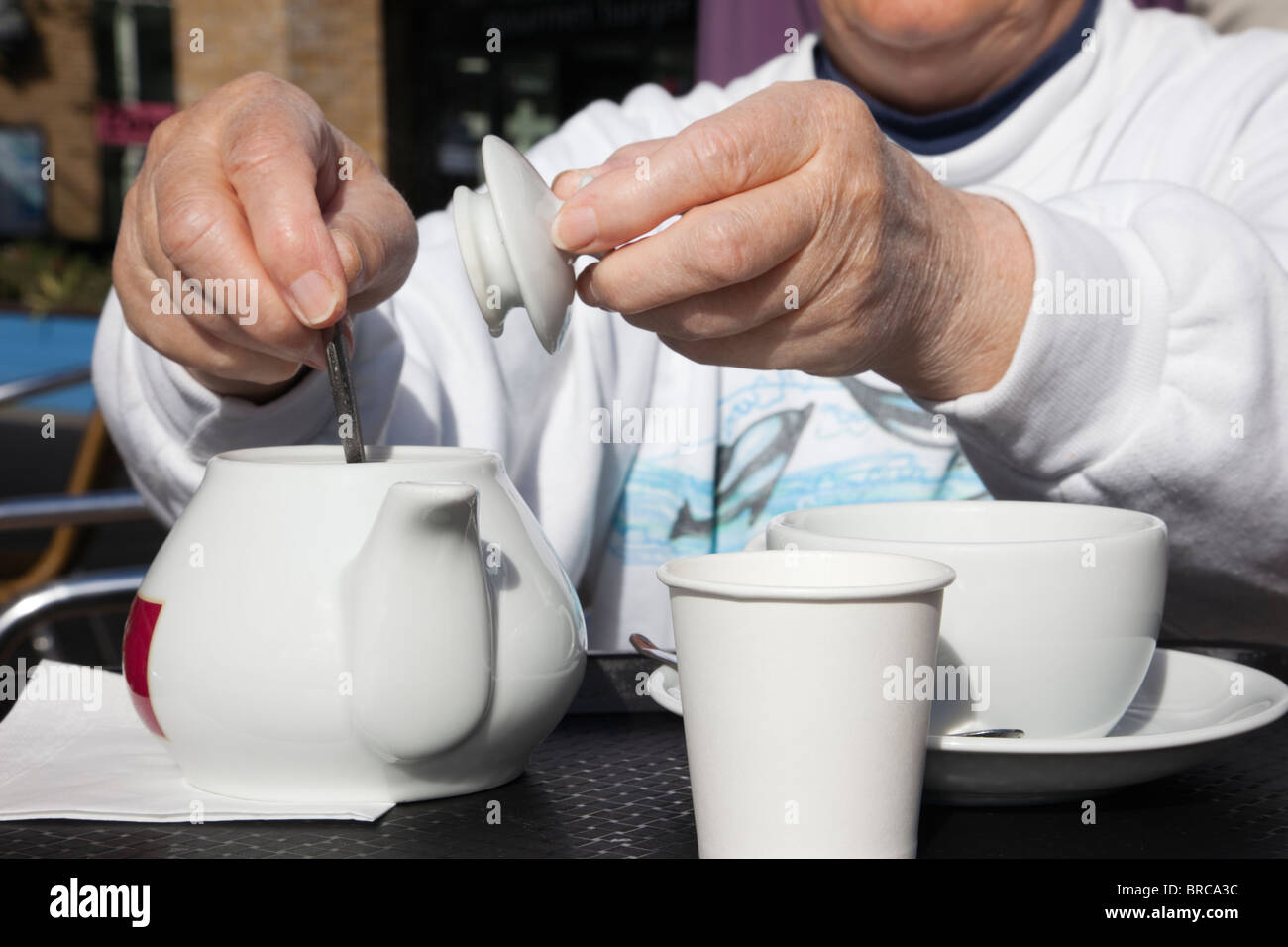 Person in a café stirring tea in a teapot. UK, Britain. Stock Photo