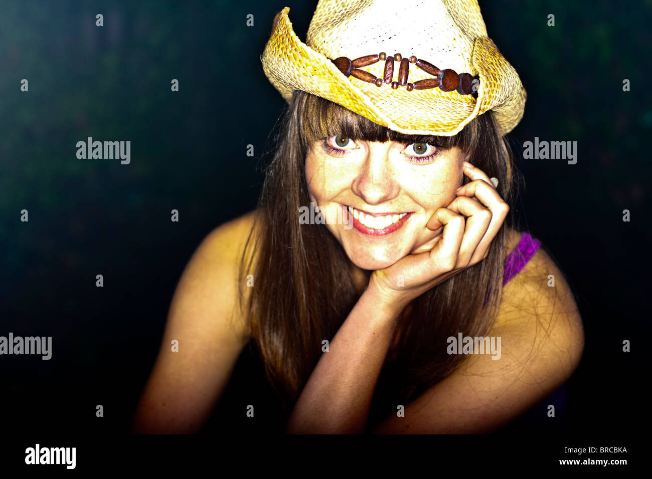 Head and shoulder portrait of a young woman smiling and wearing a cowboy hat. Stock Photo