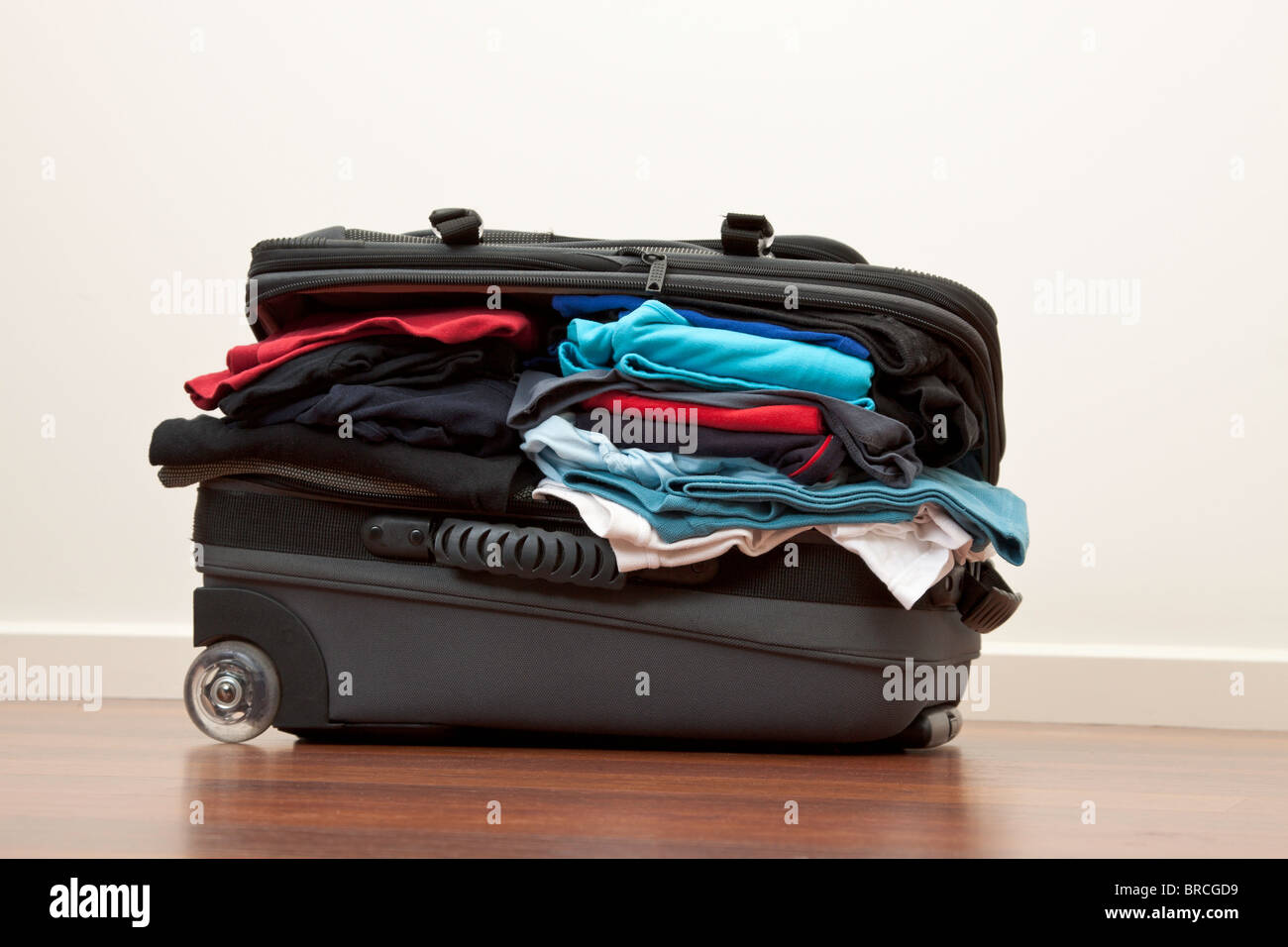 Suitcase stuffed with way to much clothes Stock Photo
