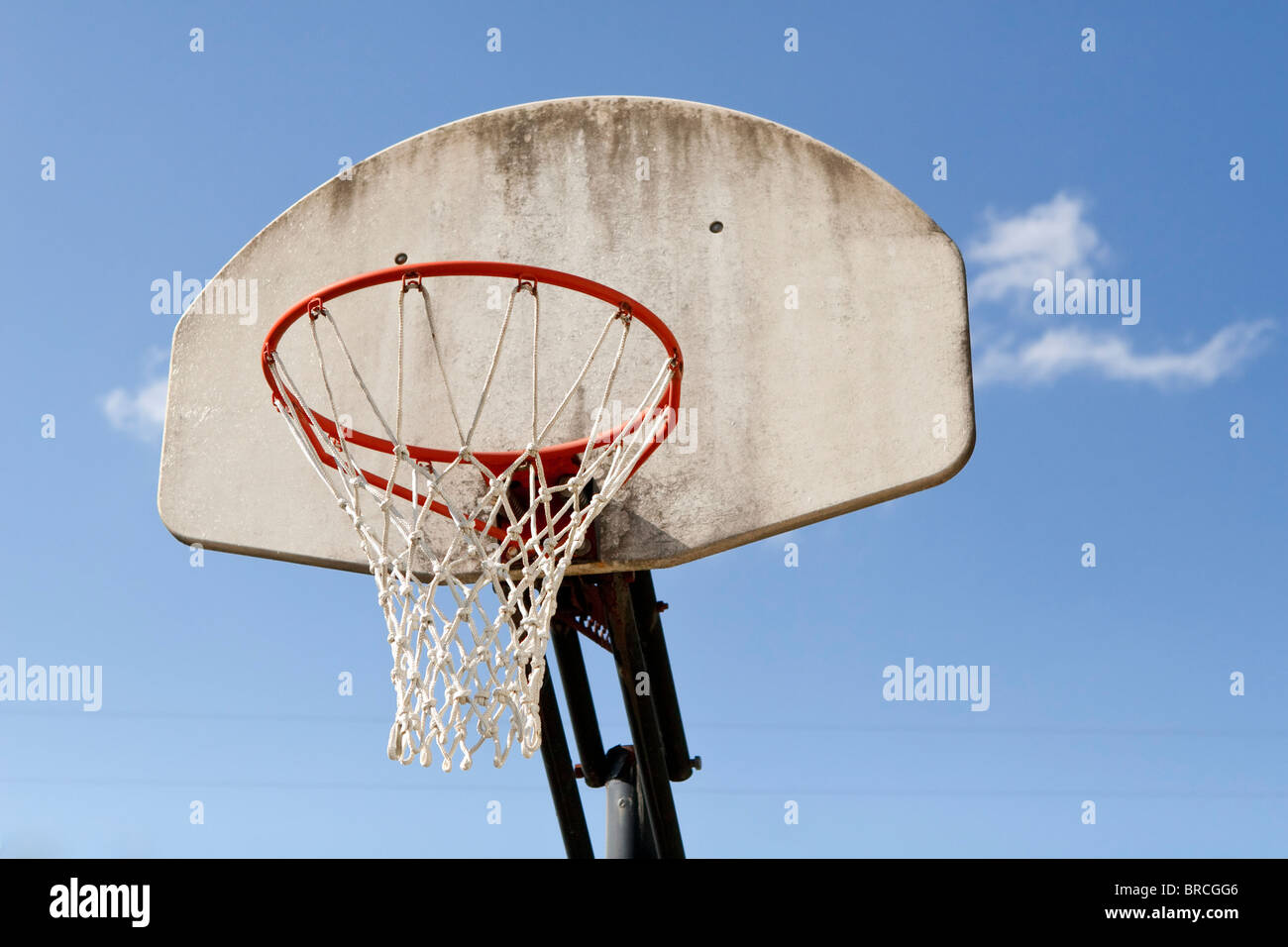 A weathered fiberglass basketball backboard, with attached rim and net  against a blue sky. Focus is on the rim and net Stock Photo - Alamy