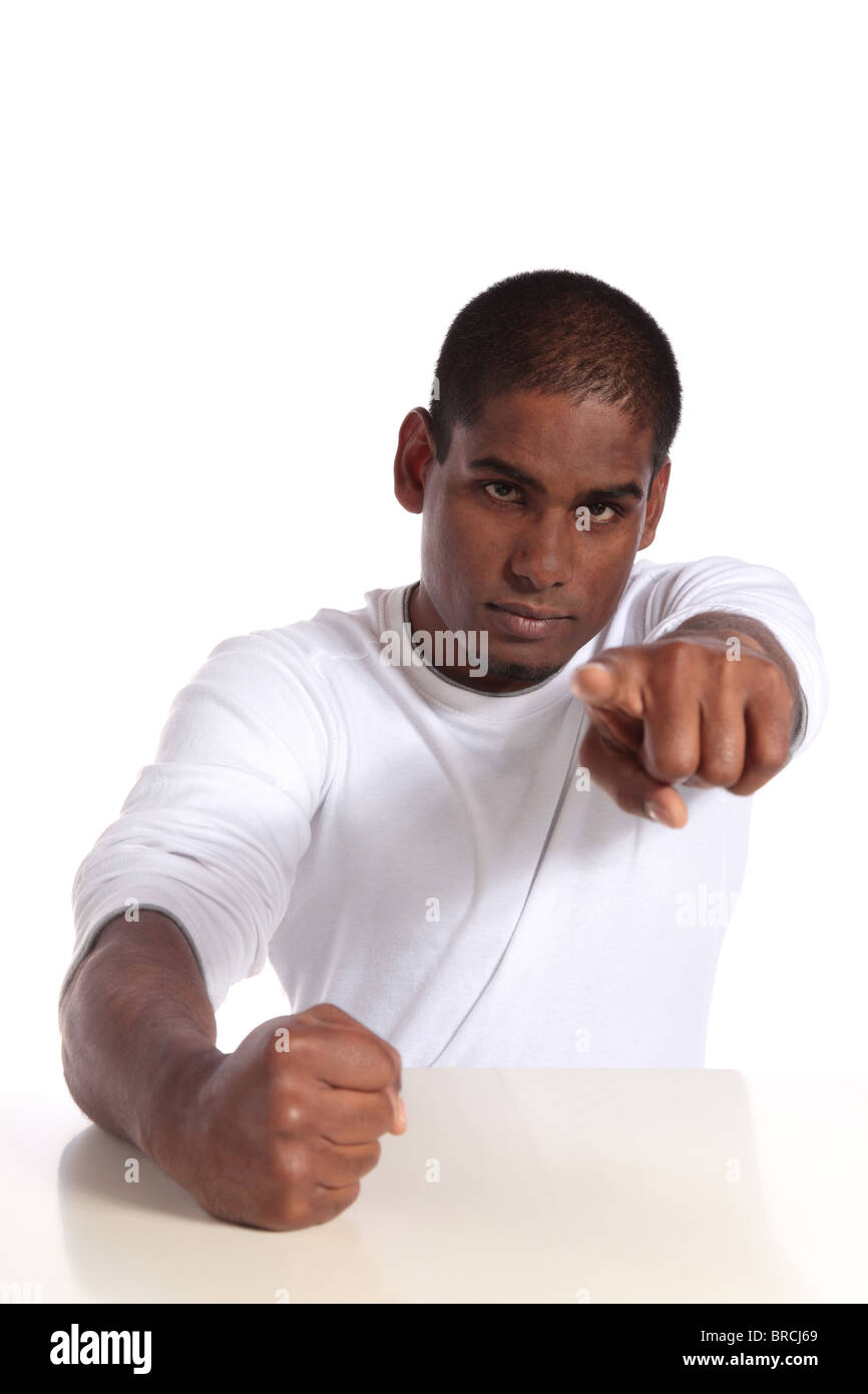 A furious dark-skinned man sitting at a table. All on white background. Stock Photo