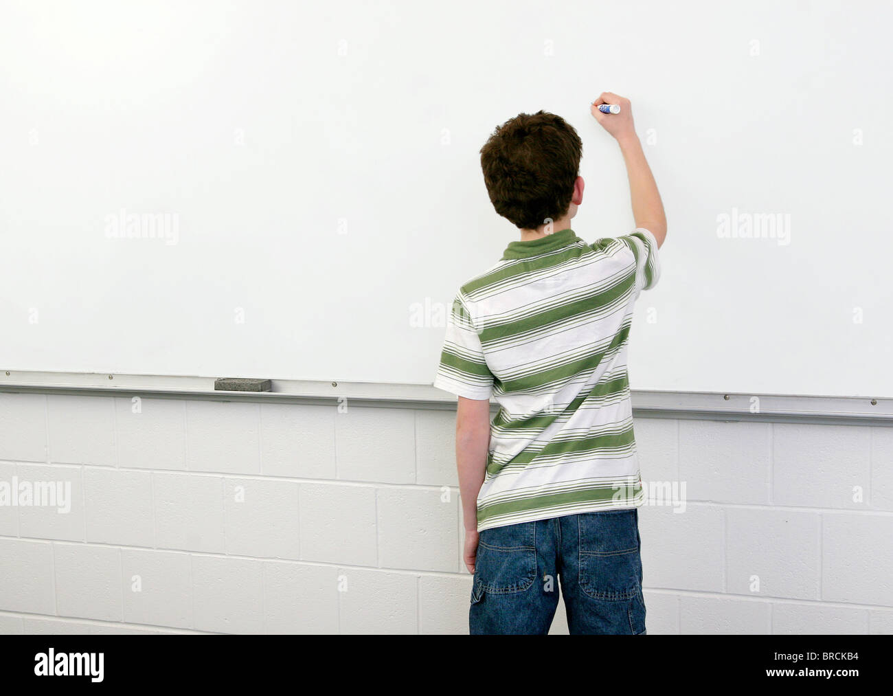 one young male student in a classroom writing on a whiteboard Stock ...