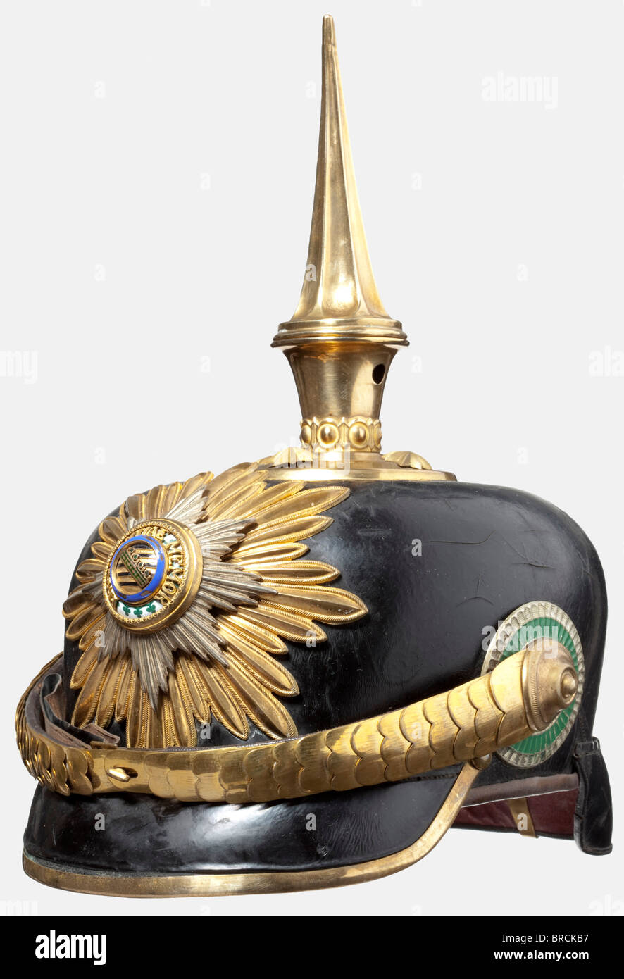 A helmet for general officers, of the Royal Saxon Army Leather body with gilt mountings, tall fluted spike. A silver, partly enamelled star with a small chip in the medallion ring set on the gilded star emblem. Convex gilt metal chinscales. Saxon style cockade. Yellow silk lining. It comes with the protective case. Cracks in the lacquer due to age, and an old pair of holes in the area of the emblem (helmet upgraded upon promotion). According to the consigner, the helmet derives from the possessions of General von der Decken. historic, historical, 19th century, , Stock Photo